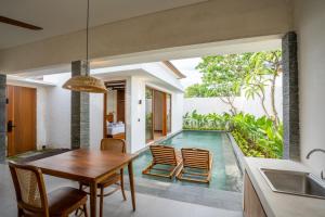 a dining room with a table and a swimming pool at Atania Villa's Bingin in Uluwatu