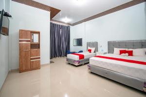 a bedroom with two beds and a television in it at RedDoorz Syariah near Danau Lut Tawar Takengon in Takengon
