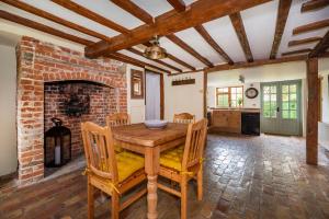 a dining room with a table and a brick fireplace at Buttercup Cottage, Hartest in Hartest