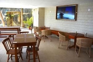 a restaurant with tables and chairs and a tv on the wall at Apartamento a Beira Mar no Flat Elegance in Natal