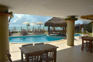 a swimming pool with tables and chairs and the ocean at Apartamento a Beira Mar no Flat Elegance in Natal