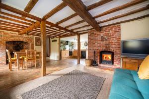 a living room with a fireplace and a tv at Buttercup Cottage, Hartest in Hartest