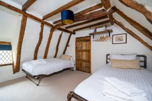 two beds in a room with wooden beams at Buttercup Cottage, Hartest in Hartest