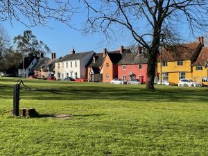 a green field with houses and a tree at Buttercup Cottage, Hartest in Hartest