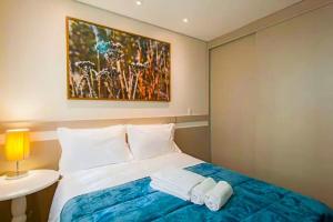 um quarto com uma cama com um quadro na parede em Flores da Montanha 301B em Gramado