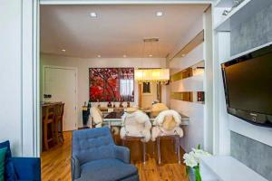 Una sala de estar con una mesa y sillas y un televisor. en Flores da Montanha 301B, en Gramado