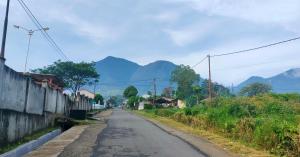 an empty street in a village with mountains in the background at Ruteng Hostel in Ruteng