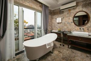 ein Badezimmer mit einer Badewanne, einem Waschbecken und einem Spiegel in der Unterkunft La Mejor Hotel & Sky Bar in Hanoi