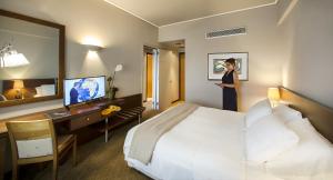 a woman standing in a hotel room with a bed at Dekelia Hotel in Athens