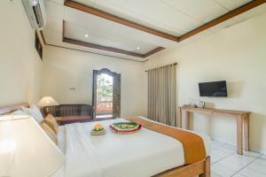 um quarto com uma grande cama branca e uma televisão em KUDESA Homestay by Pramana Villas em Ubud