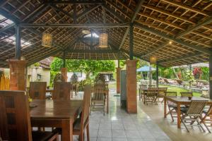 um restaurante com mesas e cadeiras e um guarda-sol em KUDESA Homestay by Pramana Villas em Ubud