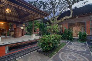uma casa com um pátio com uma árvore em KUDESA Homestay by Pramana Villas em Ubud