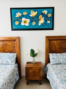 a bedroom with two beds and a painting on the wall at CASA HUELLAS EN LA ARENA in Ixtapa