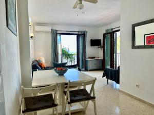 ein Wohnzimmer mit einem weißen Tisch und Stühlen in der Unterkunft Casa con terraza y hermoso jardín comunal in Nerja