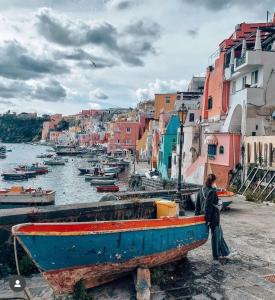 a woman walking next to a boat on the water at La casa del postino in Procida