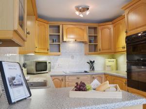 a kitchen with wooden cabinets and a bowl of fruit on a counter at Castleview West in Lochearnhead