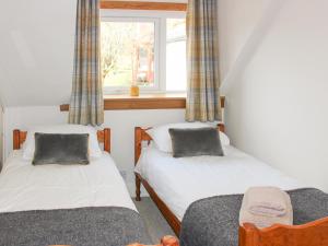 two beds in a room with a window at Castleview West in Lochearnhead