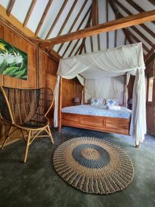 a bedroom with a canopy bed and a chair and a rug at Villa Kayu Yogyakarta in Yogyakarta