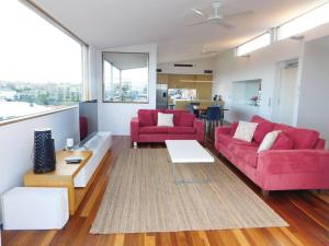 una sala de estar con 2 sofás rojos y una mesa. en Clovelly Beach House with Pool en Sídney