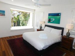 a bedroom with a white bed and a window at Clovelly Beach House with Pool in Sydney