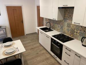 a kitchen with white cabinets and a stove and a table at Przytulne w Centrum in Ostrowiec Świętokrzyski