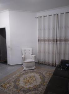 a living room with a white chair and a rug at Casa para locação in Atibaia