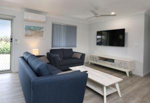 a living room with a couch and a tv and a table at Tanner St Retreat in Bargara