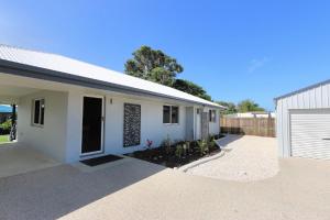 a white house with a driveway and a garage at Tanner St Retreat in Bargara