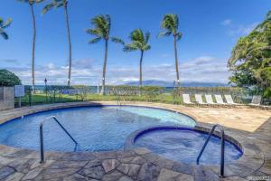 a swimming pool with palm trees in the background at Wonderful Paki Maui by the Ocean in Lahaina in Lahaina