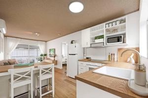 a kitchen with white cabinets and a white refrigerator at PALMA - Couples Beach Shack! in Gold Coast