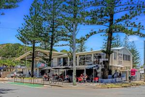 a building with tables and umbrellas on a street at PALMA - Couples Beach Shack! in Gold Coast