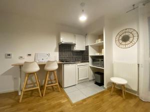 a kitchen with white appliances and two stools at Studio Cosy à 10 min de Paris in Deuil-la-Barre