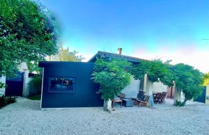una casa con una pared azul y un árbol en Villa spa, sauna et piscine couverte proche rivière Aveyron en Albias
