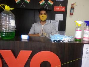 a man with a mask on his face behind a counter at OYO Sun Palace in Jabalpur