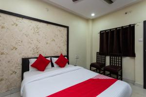 a bedroom with a large white bed with red pillows at OYO Sun Palace in Jabalpur