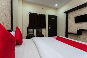 a bedroom with a large white bed with red pillows at OYO Sun Palace in Jabalpur