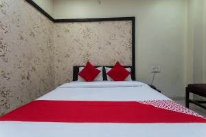 a bedroom with a white bed with red pillows at OYO Sun Palace in Jabalpur