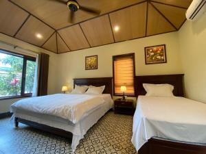 a bedroom with two beds and a window at Le Jardin De Tam Coc in Ninh Binh