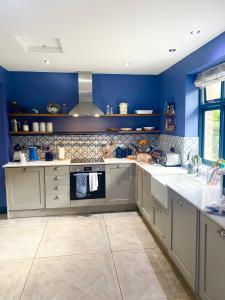 a large kitchen with blue walls and white counters at Beautiful 5 bedroom house with hot tub & fire pit in Abergavenny