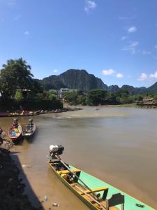 a group of boats are docked on a river at Downtown Vang Vieng Hotel in Vang Vieng
