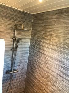 a shower in a bathroom with a brick wall at hyggeligt byhus tæt ved skov og togstation in Ålbæk +10 photos