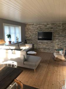 a living room with a couch and a brick wall at hyggeligt byhus tæt ved skov og togstation in Ålbæk