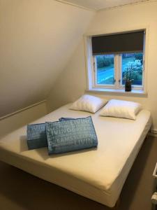 a bed with two pillows on it with a window at hyggeligt byhus tæt ved skov og togstation in Ålbæk