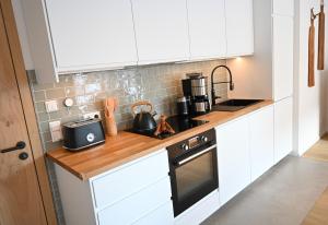 a kitchen with white cabinets and a stove top oven at FEWO RISSERKOGEL das Original mit großem Garten in Bad Wiessee