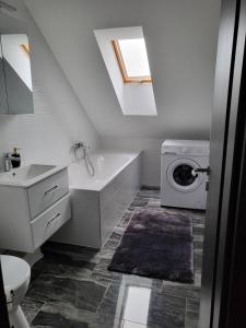 ein Badezimmer mit einem Waschbecken und einer Waschmaschine in der Unterkunft Flower Apartman 5 