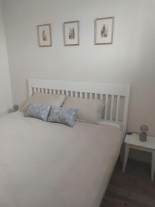 a white bed with three pictures on the wall at APARTMENT KORTINE in Sečovlje