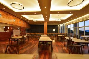 a restaurant with wooden tables and chairs and windows at Senomoto Kogen Hotel in Minamioguni