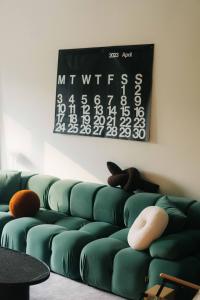 - un canapé vert dans un salon avec un calendrier mural dans l'établissement 無處 Nowhere Retreat 獨棟空間, à Yilan