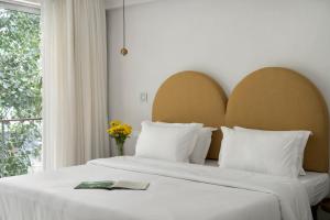 a bedroom with a bed with white sheets and a window at Bungalow 157 in New Delhi