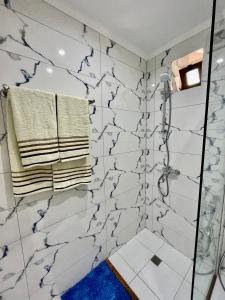 a bathroom with white marble walls and a shower at GUGA Host House in Sarandë